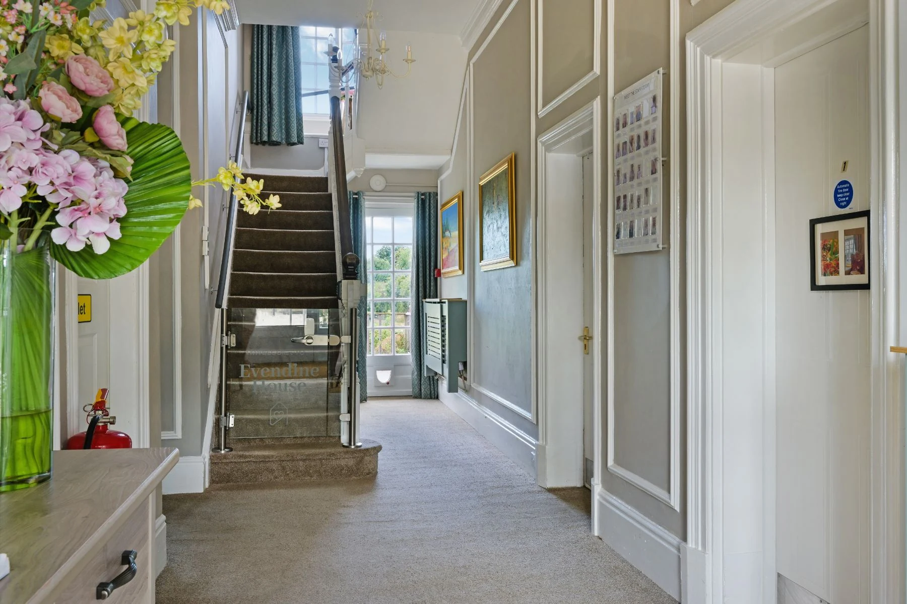 Panelled entrance hall with staircase and fresh flowers